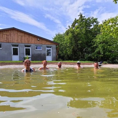 Menschen baden im zukünftigen Gänseteich von Haus #2 im Land der Tiere, dem veganen Tierschutzzentrum zwischen Hamburg, Berlin und Lüneburg