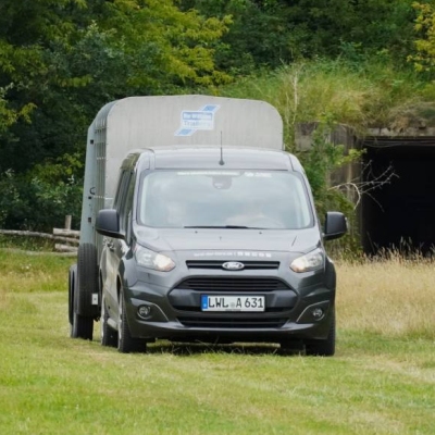 Ein Auto mit Tierhänger fährt in Richtung der Kamera