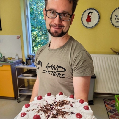 Mensch Bene hält eine vegane Torte in die Kamera
